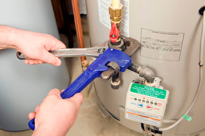 Plumber repairing water heater pipe connection in Boynton Beach, Florida home